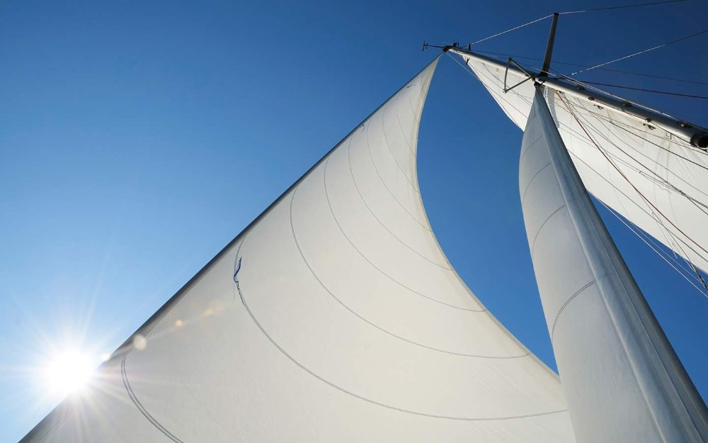 View of sailboat's white sails from deck