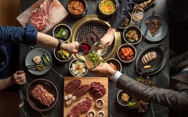 Set table at COTE's showcasing it butcher's feast variety of meats, greens and side dishes