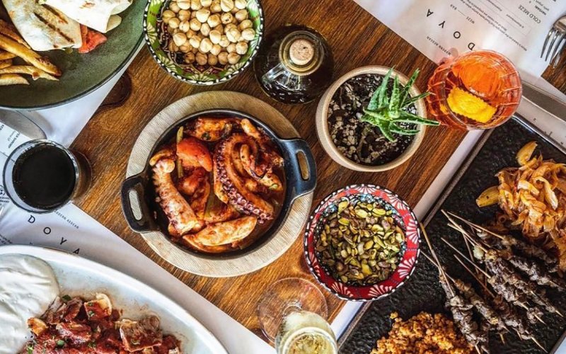 Table of an array of dishes showcasing diverse flavors and colors at Doya