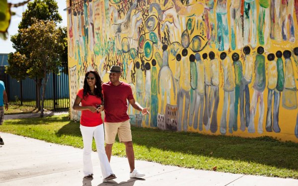 Couple strolling by Purvis Young mural in Overtown